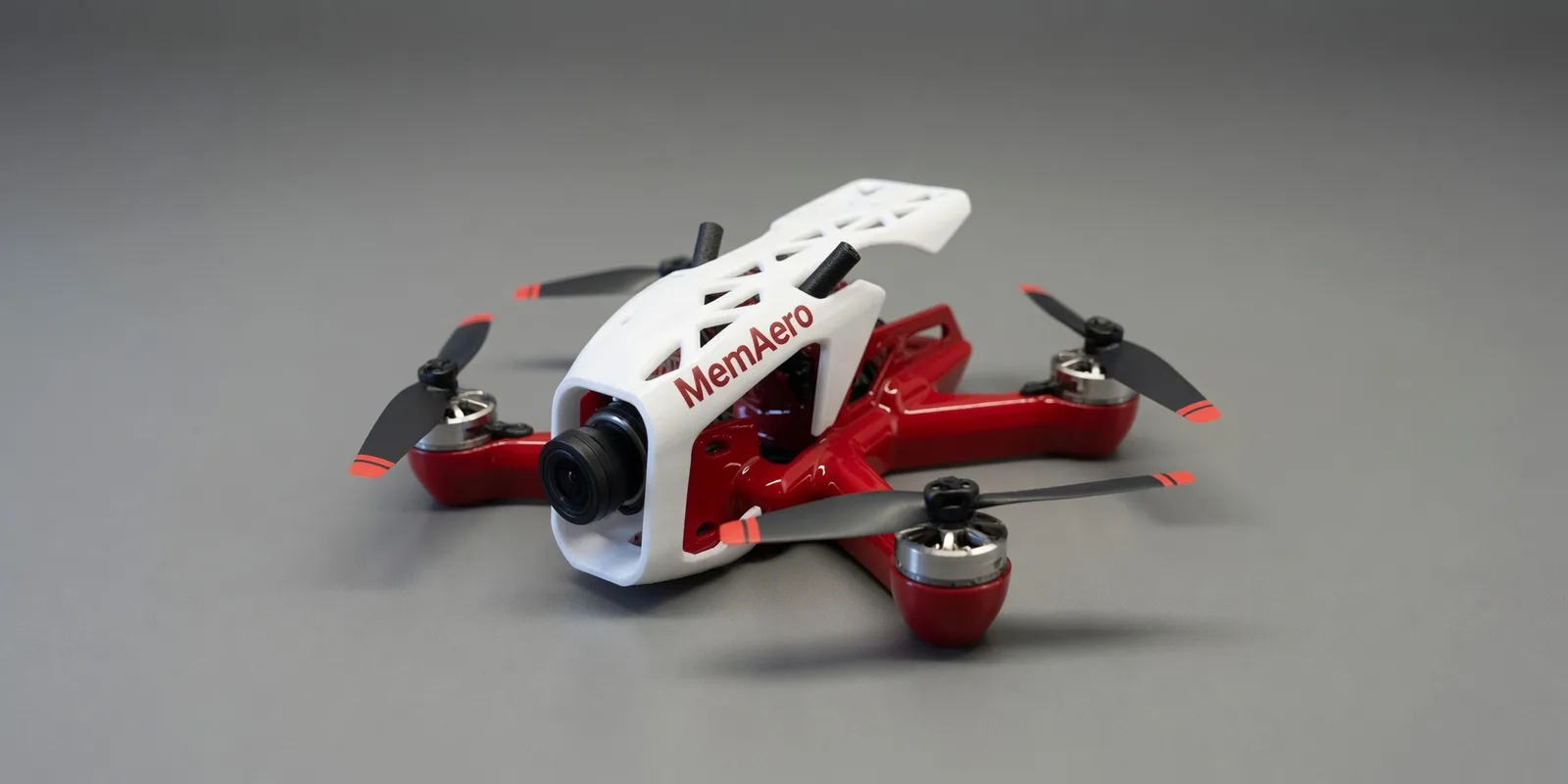 MemAero Aero 2 5-inch FPV freestyle drone — red and white airframe with 3D-printed white canopy, 3/4 front-left view (design render)